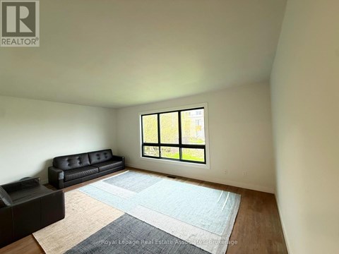A living room with a black couch and a large window.