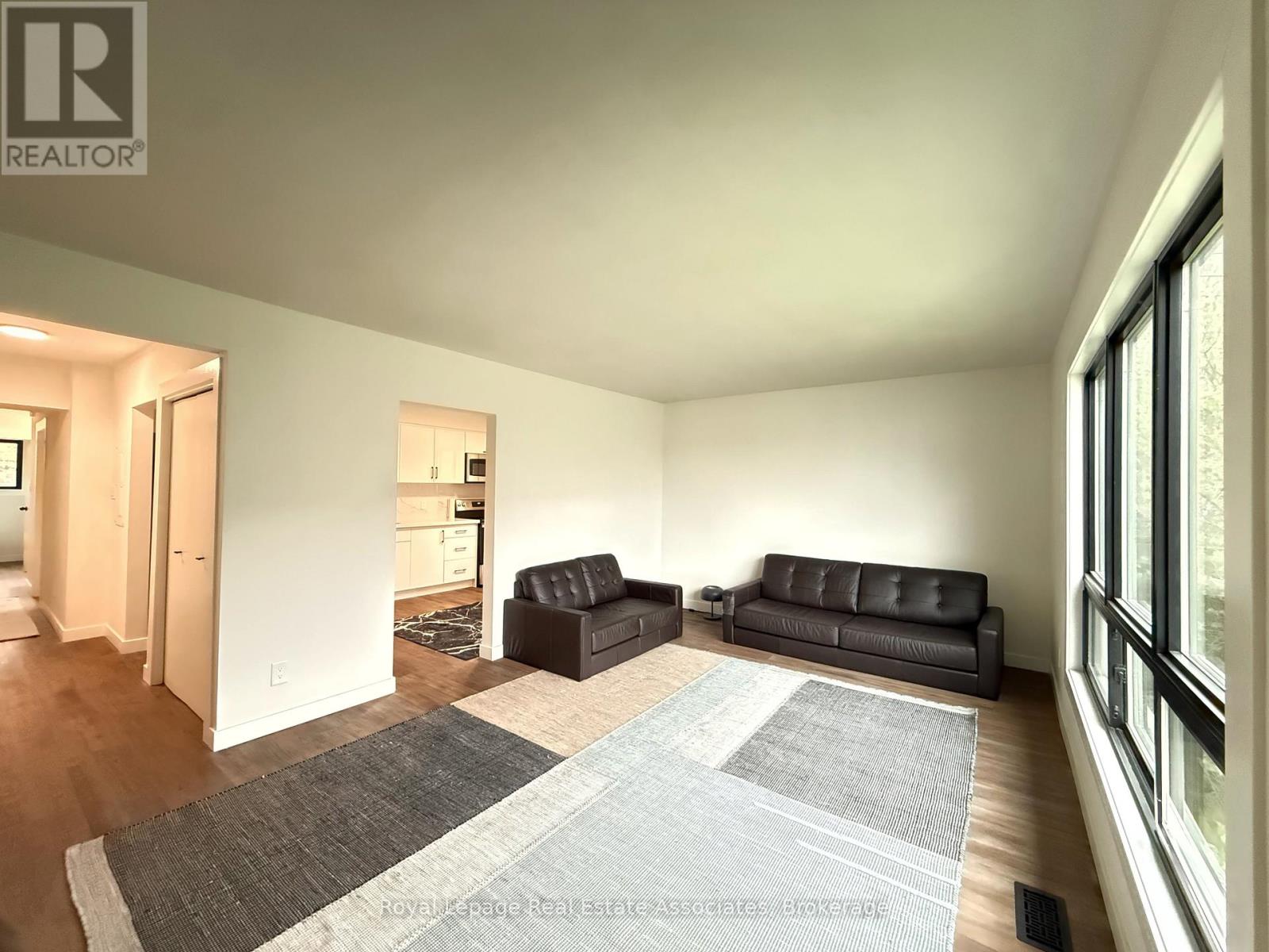 A living room with two black leather sofas and a grey rug.