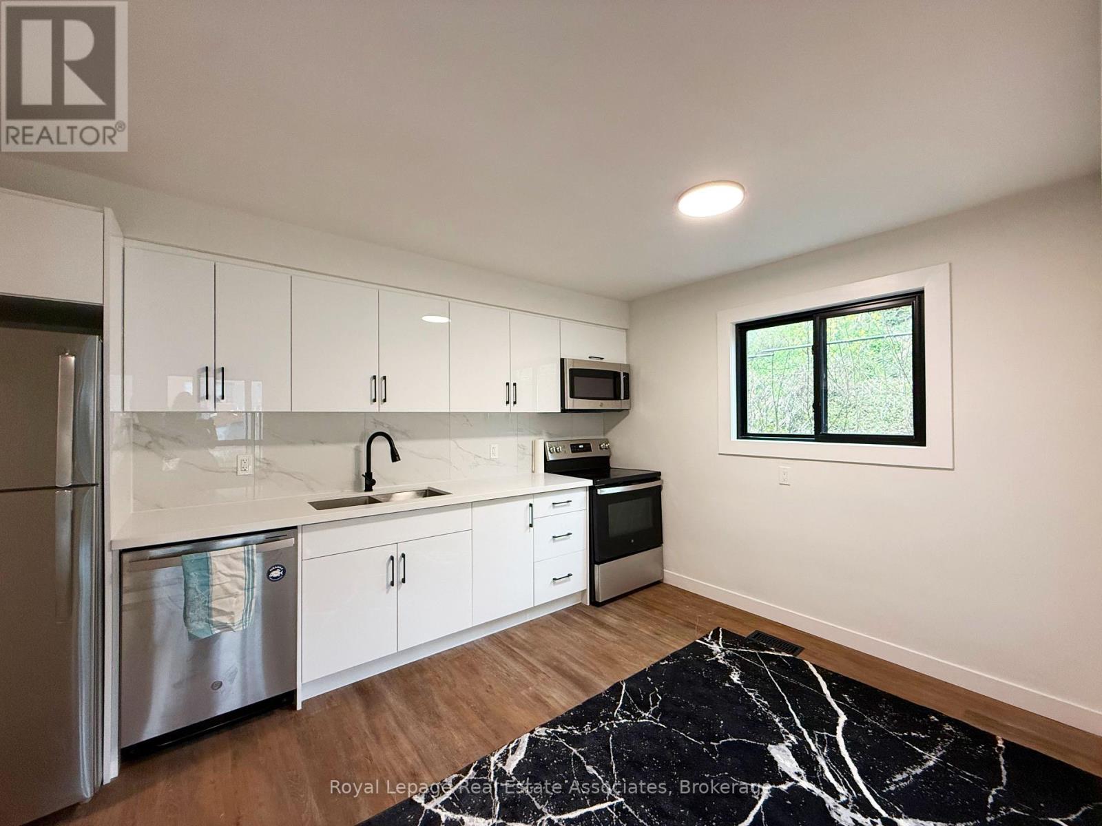 A kitchen with white cabinets and a black and white rug on the floor.