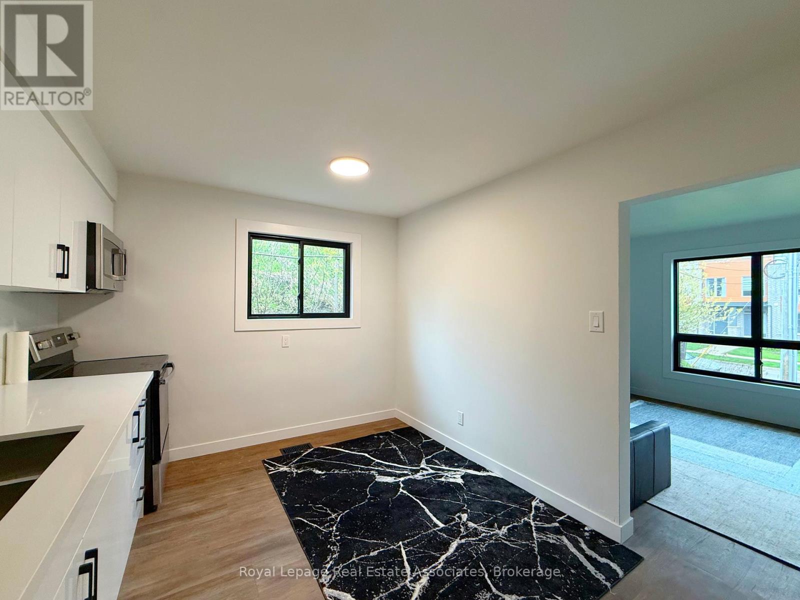 A kitchen with white cabinets and a black and white marble floor mat.