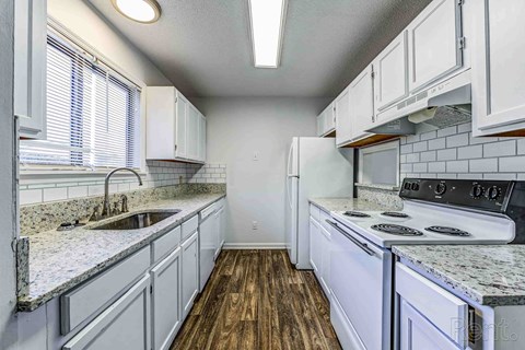 A kitchen with white cabinets and a granite countertop.