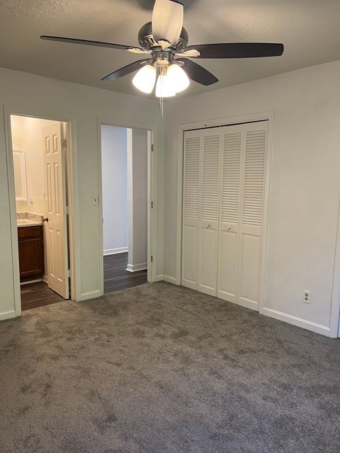 A room with a ceiling fan and carpeted floor.