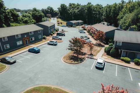 A parking lot with cars and a few trees in the background.