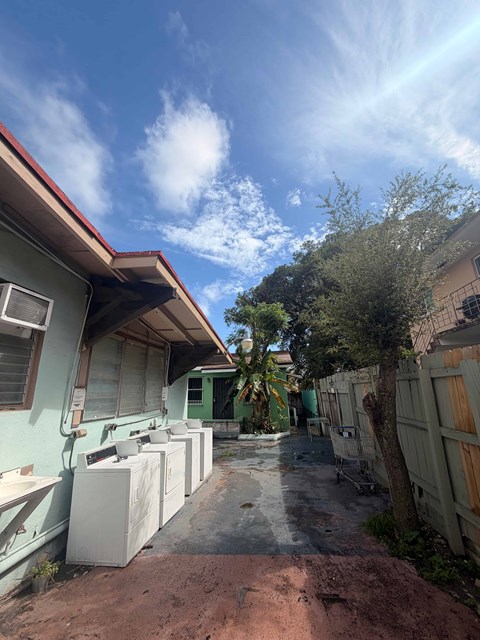 A row of houses with green trees in front.