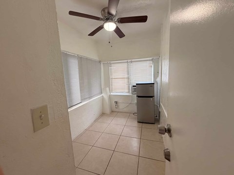 A room with a ceiling fan and a window with blinds.
