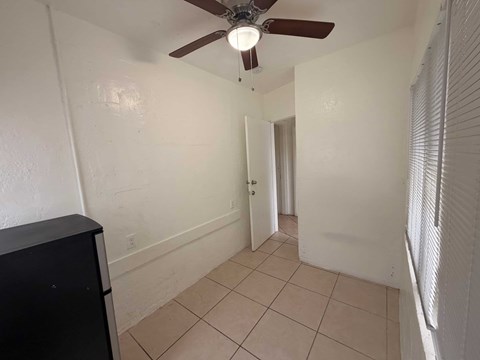 A room with a ceiling fan and tiled floor.