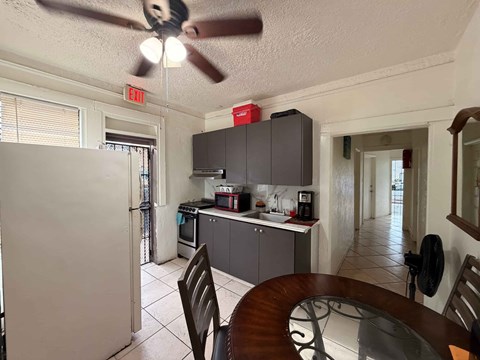A kitchen with a white refrigerator and a ceiling fan.