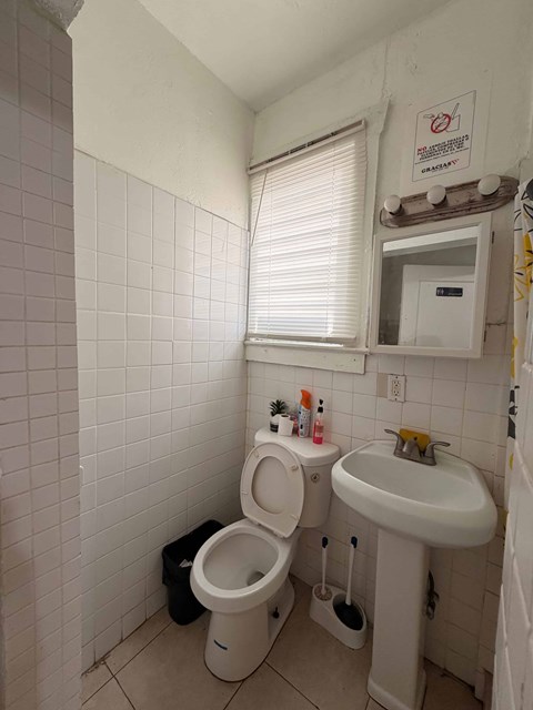 A bathroom with a toilet, sink and trash can.