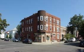 A red brick building with a white car parked in front.