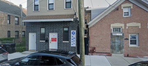 A black car is parked in front of a brick building.