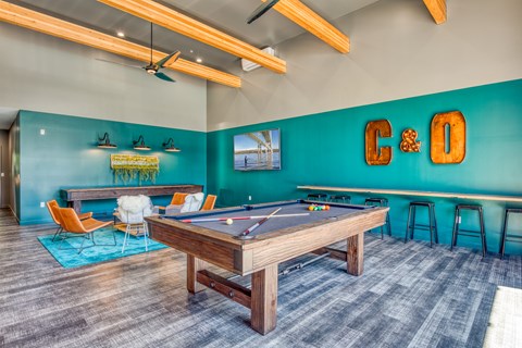 A room with a pool table and a bar area.