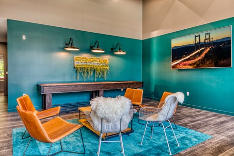 A living room with a blue wall and a painting of a bridge.