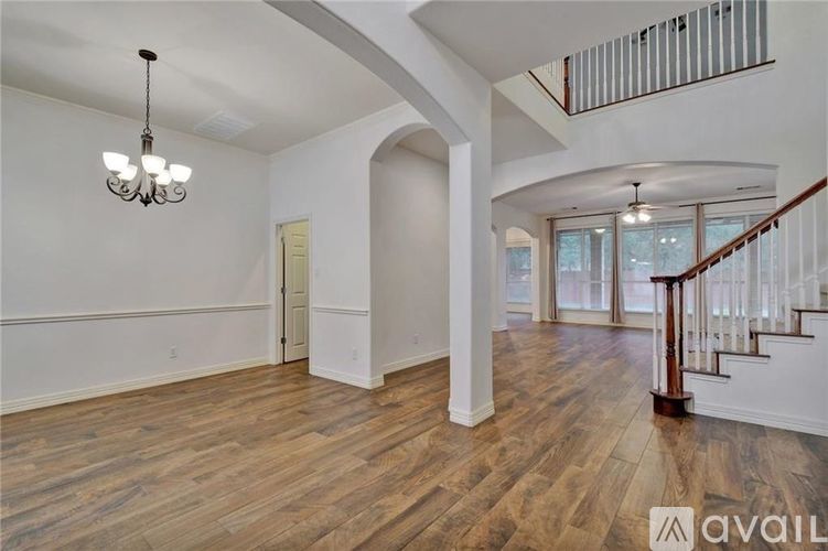 A spacious room with wooden flooring and a staircase with a metal railing.