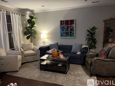A living room with a blue couch and a painting on the wall.
