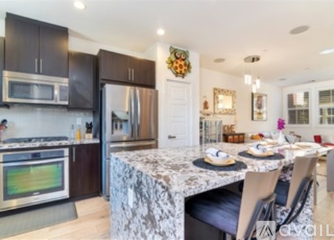 A kitchen with a marble table and modern appliances.