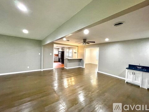 A spacious room with wooden floors and a ceiling fan.