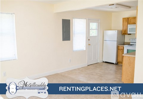 A kitchen area with a white refrigerator, microwave, and oven, and a door leading to another room.