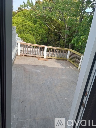 A balcony with a railing and trees in the background.