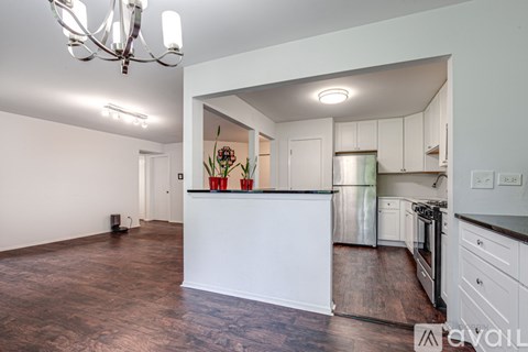 A kitchen with a white counter and brown floors.
