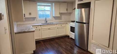 A kitchen with white cabinets and a stainless steel refrigerator.