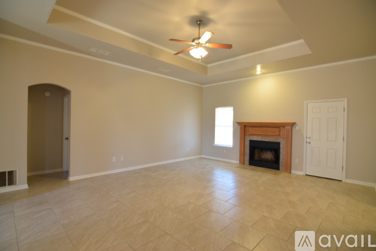 A spacious room with a fireplace and a ceiling fan.