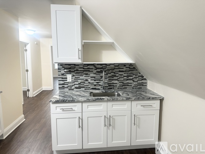 A kitchen with white cabinets and a stone backsplash.