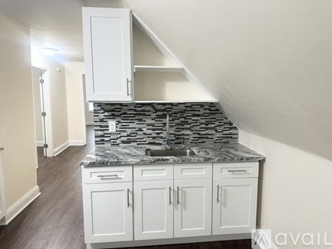 A kitchen with white cabinets and a stone backsplash.