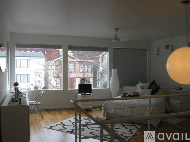 A bedroom with a bed, a dresser, and a window overlooking a cityscape.