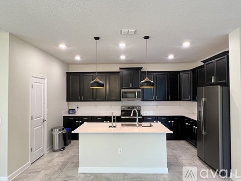 A modern kitchen with black cabinets and a white island.