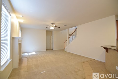 A spacious room with a ceiling fan and a staircase.