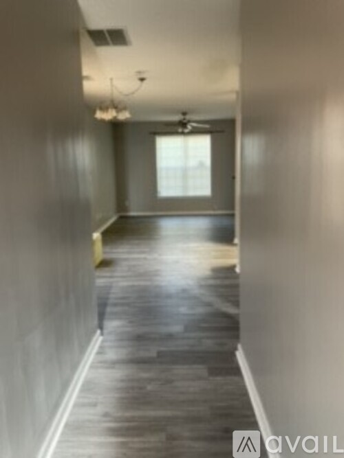 A long hallway with a fan and lighting fixture.