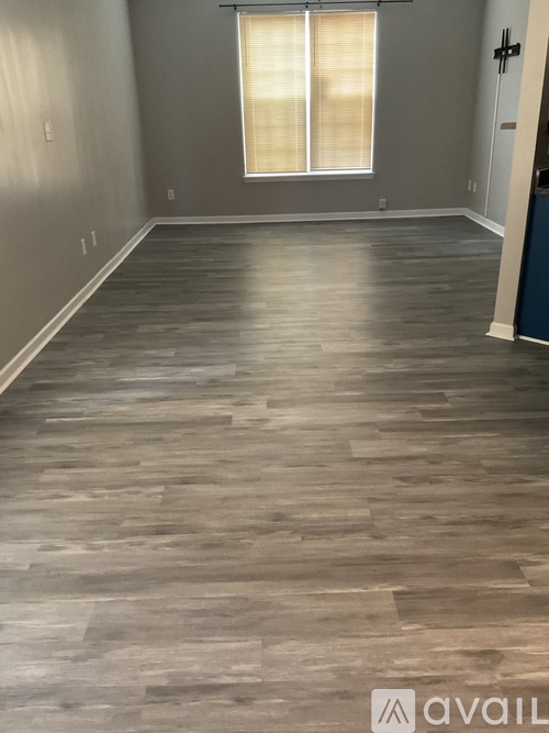 A room with wooden flooring and a window with blinds.