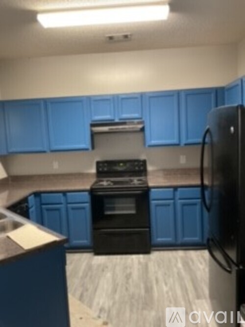 A kitchen with blue cabinets and a black refrigerator.