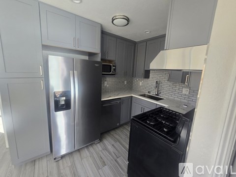 A kitchen with a stainless steel refrigerator and black stove top oven.
