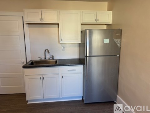 A kitchen with white cabinets and a stainless steel refrigerator.