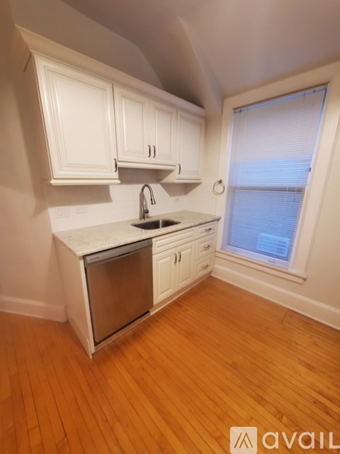 A kitchen with white cabinets and a wooden floor.