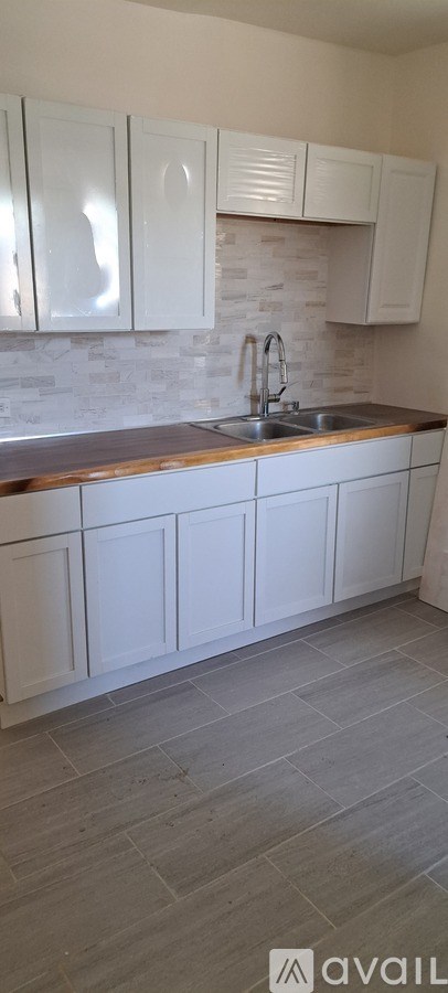 A kitchen with white cabinets and a stone backsplash.