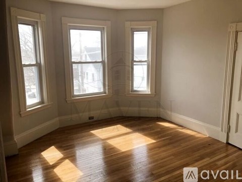 A room with wooden floors and three windows.