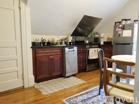 A kitchen with a refrigerator, oven, and a wooden floor.