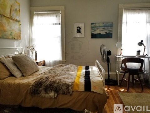 A bedroom with a bed covered in a fur throw and a striped blanket, a chair, and a painting on the wall.