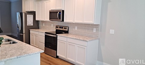 A kitchen with white cabinets and a granite counter.