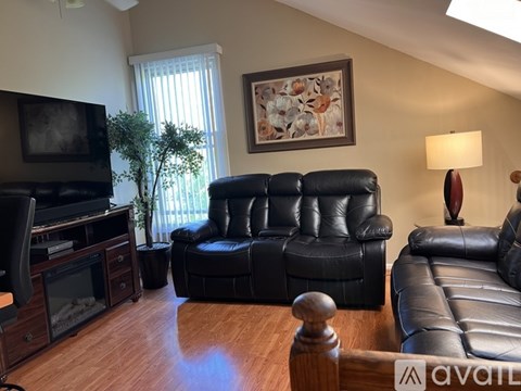 A living room with black leather furniture and a flat screen TV.