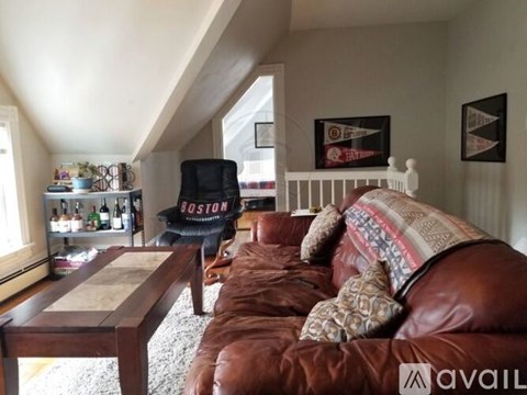 A living room with a brown leather couch and a Boston chair.