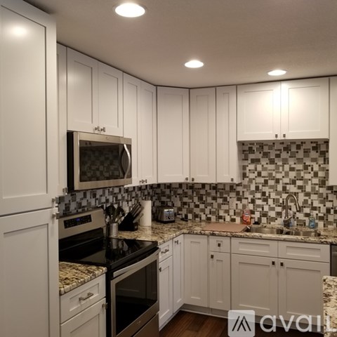 A kitchen with white cabinets and a black countertop.
