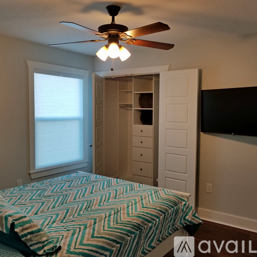 A bedroom with a bed and a ceiling fan.