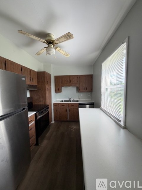 A kitchen with a refrigerator, cabinets, and a ceiling fan.