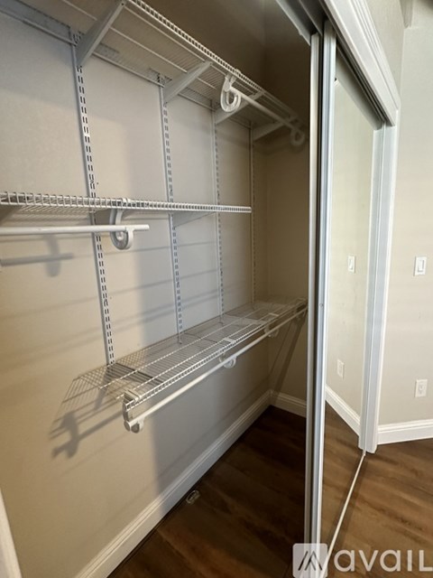 A white walk-in closet with shelving and a door open.