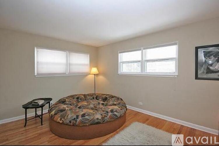 A bedroom with a round bed, a small table, and a framed picture on the wall.