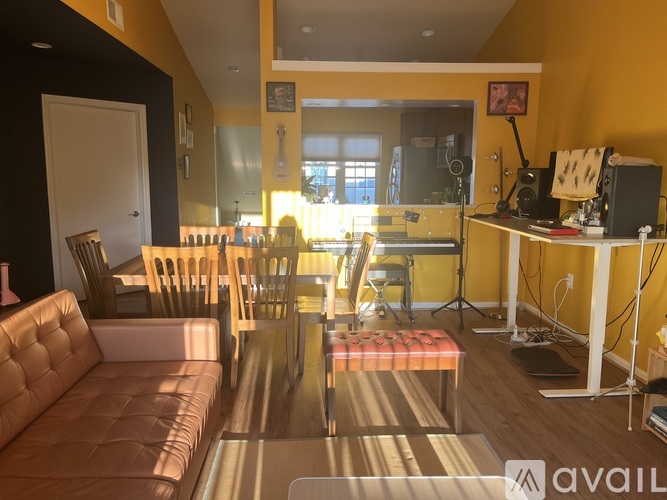 A living room with a brown leather couch and a white table with a computer on it.