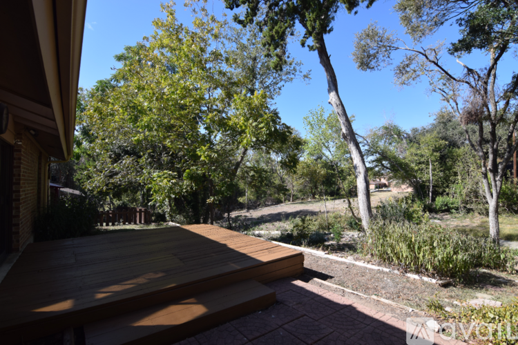 A wooden deck overlooks a garden with a variety of trees.